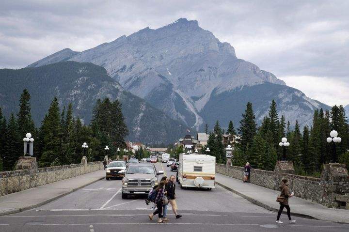 People walk across a street in Banff, Alta., in Banff National Park, Friday, July 21, 2017. 