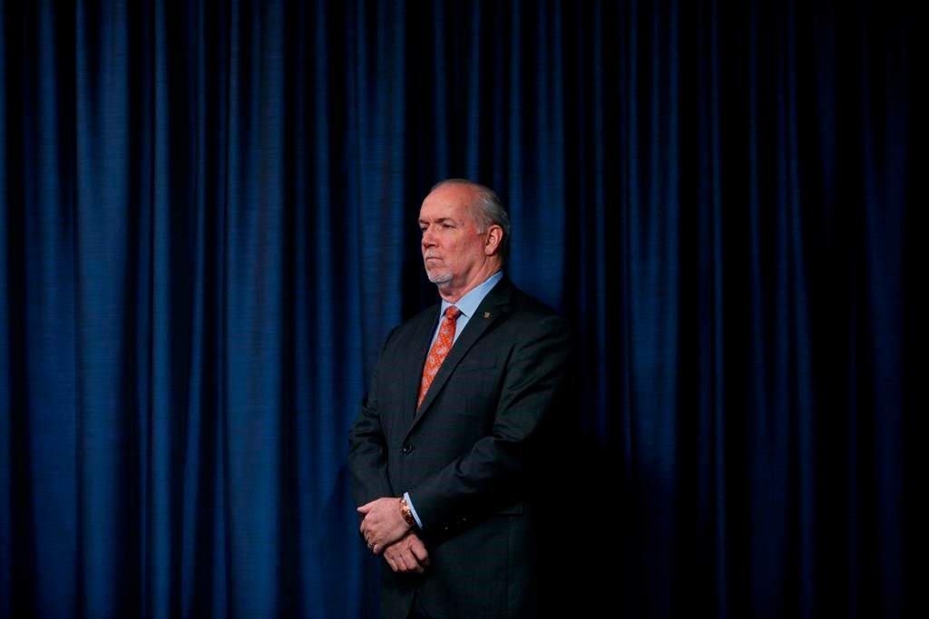 Premier John Horgan listens to questions over the phone from media as he joins Minister Mike Farnsworth to provide government measures in regards to the COVID-19 pandemic during a press conference in the press gallery at Legislature in Victoria, B.C., on Thursday March 26, 2020. THE CANADIAN PRESS/Chad Hipolito.
