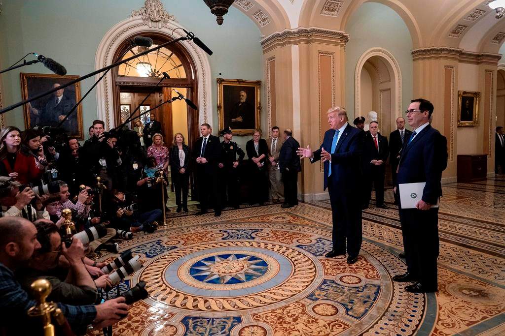 President Donald Trump, joined by Treasury Secretary Steven Mnuchin, right, speaks to reporters after meeting with Republican senators, on Capitol Hill in Washington, Tuesday, March 10, 2020. Trump wants Congress to pass payroll tax relief as he looks to calm financial markets' fears over the impact of the coronavirus epidemic. (AP Photo/J. Scott Applewhite).