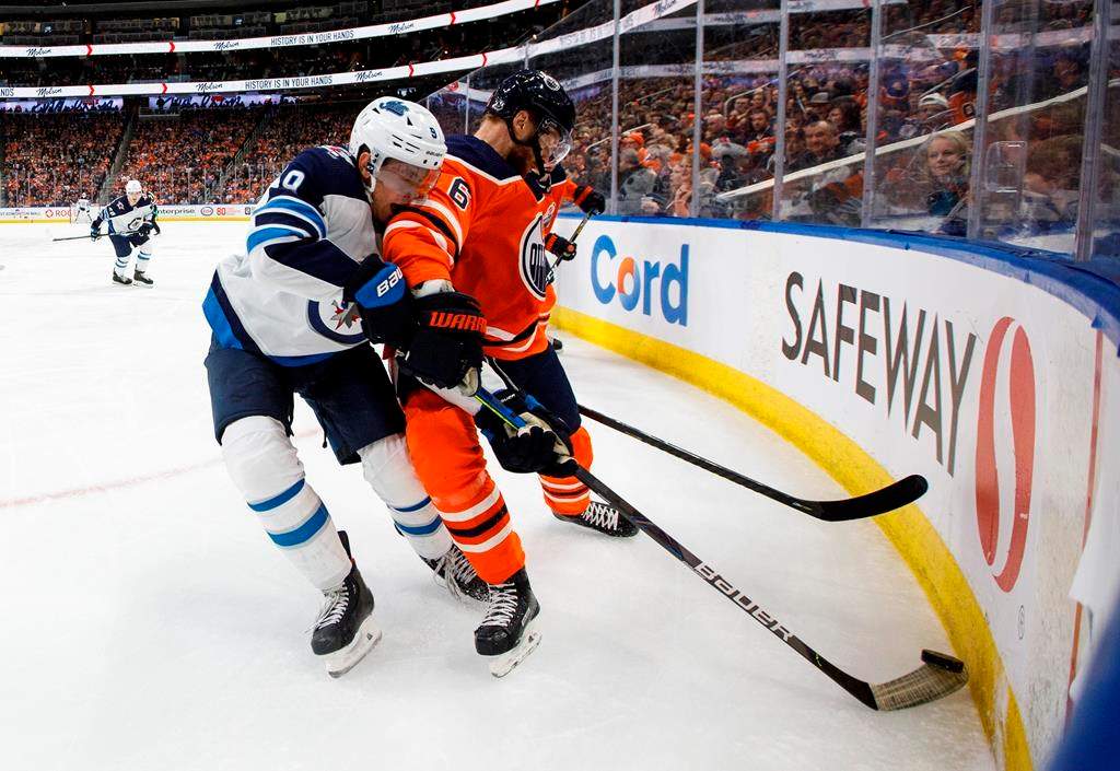 The Winnipeg Jets’ Andrew Copp (9) and the Edmonton Oilers’ Adam Larsson (6) battle for the puck during third-period NHL action in Edmonton, Saturday, Feb. 29, 2020. THE CANADIAN PRESS/Jason Franson