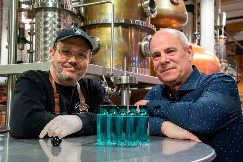 Spirit of York Head Distiller Mark Harrop (left) and founder Gerry Guitor pose with bottles of distillery-made hand sanitizer in Toronto on Wednesday March 18, 2020.