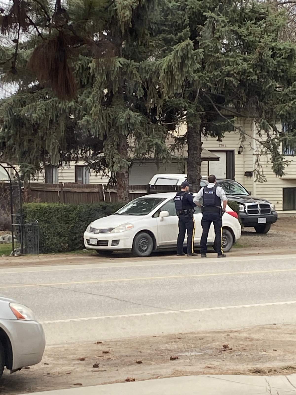 Two Kelowna Mounties stand outside a home where shots were allegedly fired on Friday.