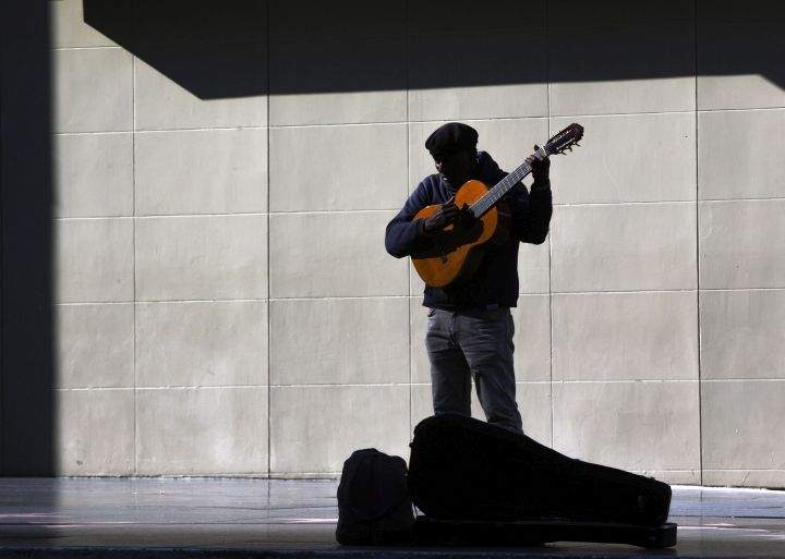A lone street performer tunes his guitar on the deserted Hollywood Boulevard in Los Angeles on Tuesday, March 24, 2020. 