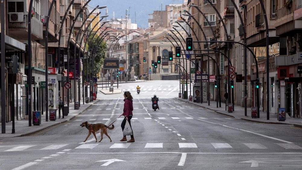 A woman walks her dog on an almost empty street in Murcia, southeast Spain, March 19, 2020.