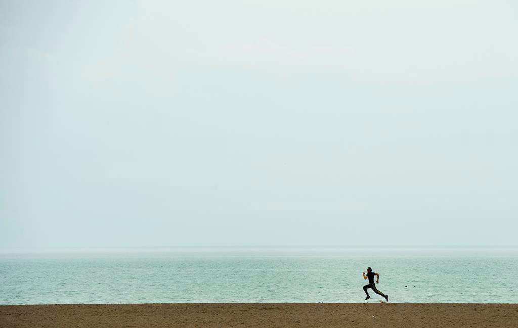 A lone man gets exercise at Woodbine Beach in Toronto on Thursday, March 26, 2020. CANADIAN PRESS/Nathan Denette.