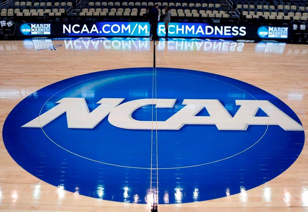 FILE - In this March 18, 2015, file photo, the NCAA logo is displayed at center court as work continues at The Consol Energy Center in Pittsburgh, for the NCAA college basketball tournament. The NCAA took a significant step toward allowing all Division I athletes to transfer one time without sitting out a season of competition. A plan to change the waiver process is expected to be presented to the Division I Council in April, 2020. If adopted, new criteria would go into effect for the 2020-21 academic year and be a boon for athletes in high-profile sports such as football and men's and women's basketball. (AP Photo/Keith Srakocic, File).