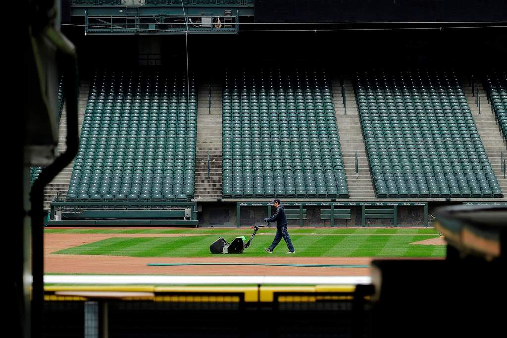 A grounds crew worker cuts the infield in front of empty seats at T-Mobile Park in Seattle, March 26, 2020, around the time when the first pitch would have been thrown in the Mariners' Opening Day baseball game against the visiting Texas Rangers.