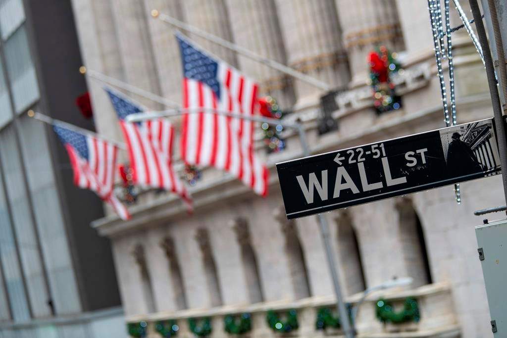 FILE - In this Jan. 3, 2020 file photo, the Wall St. street sign is framed by American flags flying outside the New York Stock Exchange in New York. (AP Photo/Mary Altaffer, File).