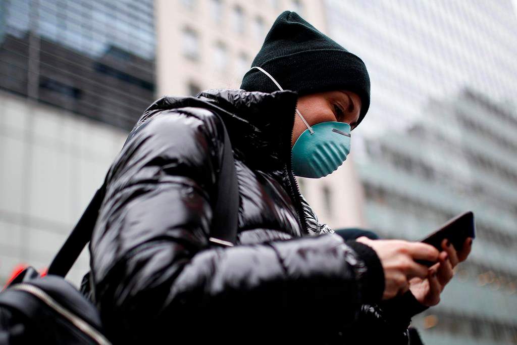 Pedestrian uses her phone while wearing a face mask in Herald Square, Thursday, March 12, 2020, in New York. (AP Photo/John Minchillo)