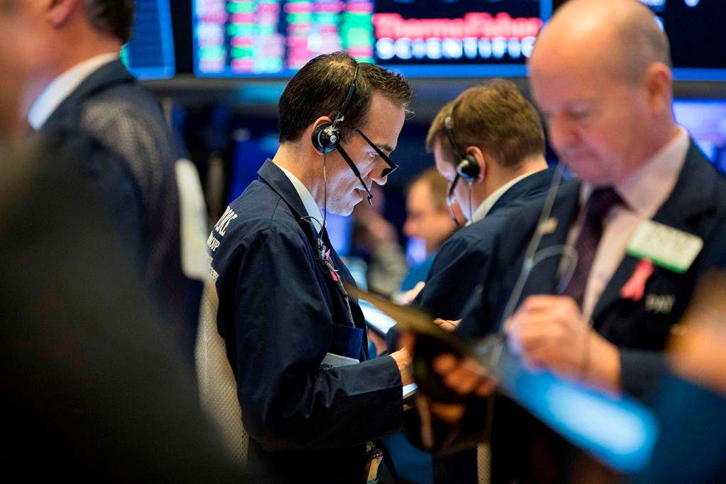 This photo provided by the New York Stock Exchange, Thursday, March 19, 2020, shows trader Gregory Rowe, center, as he works on the trading floor.