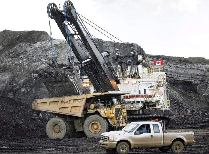 A pickup truck passes a mining shovel filling a haul truck at an oilsands mine near Fort McMurray, Alta., in this July 9, 2008 file photo. A million Canadians are asking the federal government to focus any bailout of the oil industry on workers and families, not corporations. 
