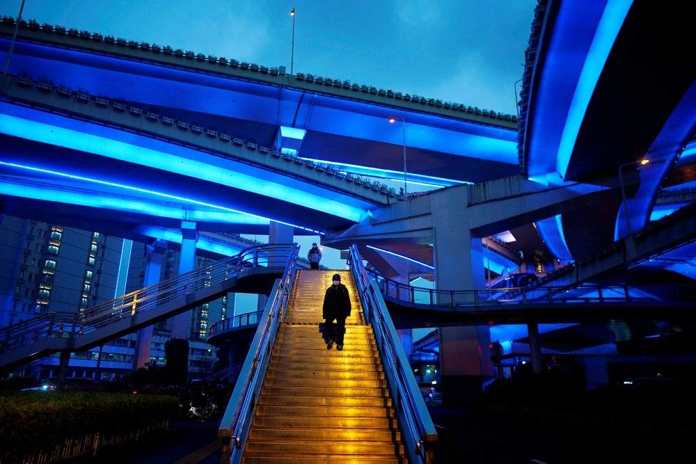 People wearing protective face masks are seen on an overpass following an outbreak of the novel coronavirus in downtown Shanghai, China, March 13, 2020.