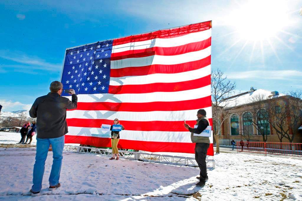 Supporters of Democratic presidential candidate Bernie Sanders take pictures in front of a large American flag before a rally Monday, March 2, 2020, in Salt Lake City. Sanders is making a stop in Salt Lake a day before Super Tuesday primaries, which Utah is a part of.