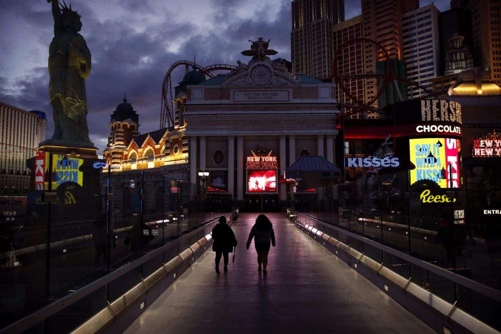 People walk along the Las Vegas Strip, devoid of the usual crowds, after casinos were ordered to shut down due to the novel coronavirus outbreak, Wednesday, March 18, 2020, in Las Vegas.