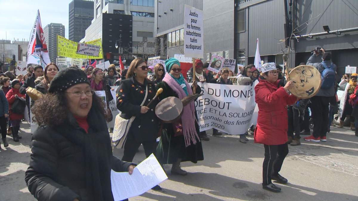 Montreal women march with signs on Ste-Catherine Street on International Women’s Day.