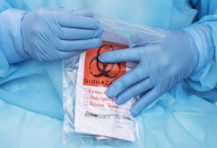 A health-care worker closes a biohazard bag after issuing a coronavirus test in Montreal, Sunday, March 29, 2020.