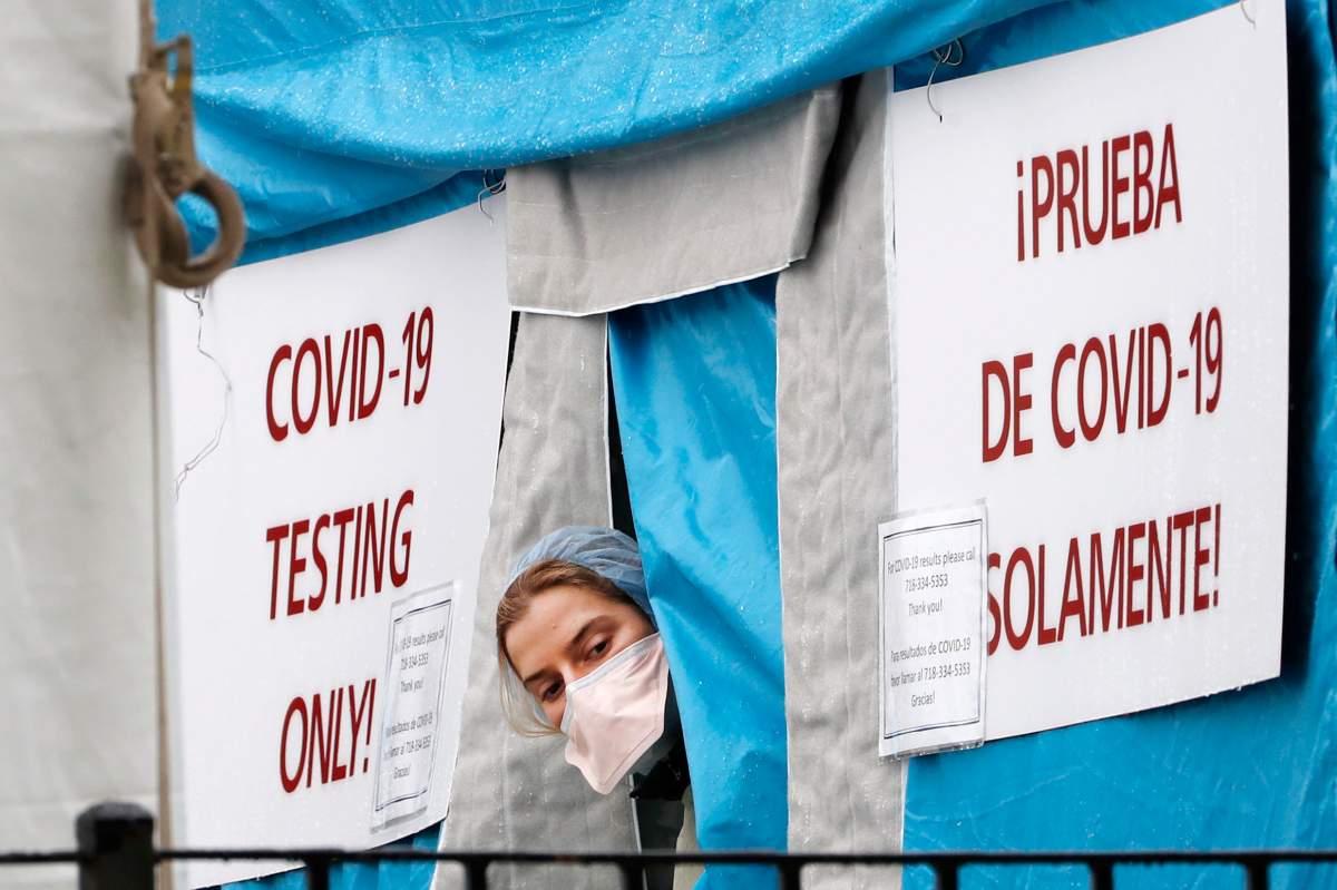 A medical worker sticks her head outside a COVID-19 testing tent set up outside Elmhurst Hospital Center in New York, Saturday, March 28, 2020. The hospital is caring for a high number of coronavirus patients in the city, and New York leads the nation in the number of cases, according to Johns Hopkins University, which is keeping a running tally. (AP Photo/Kathy Willens).