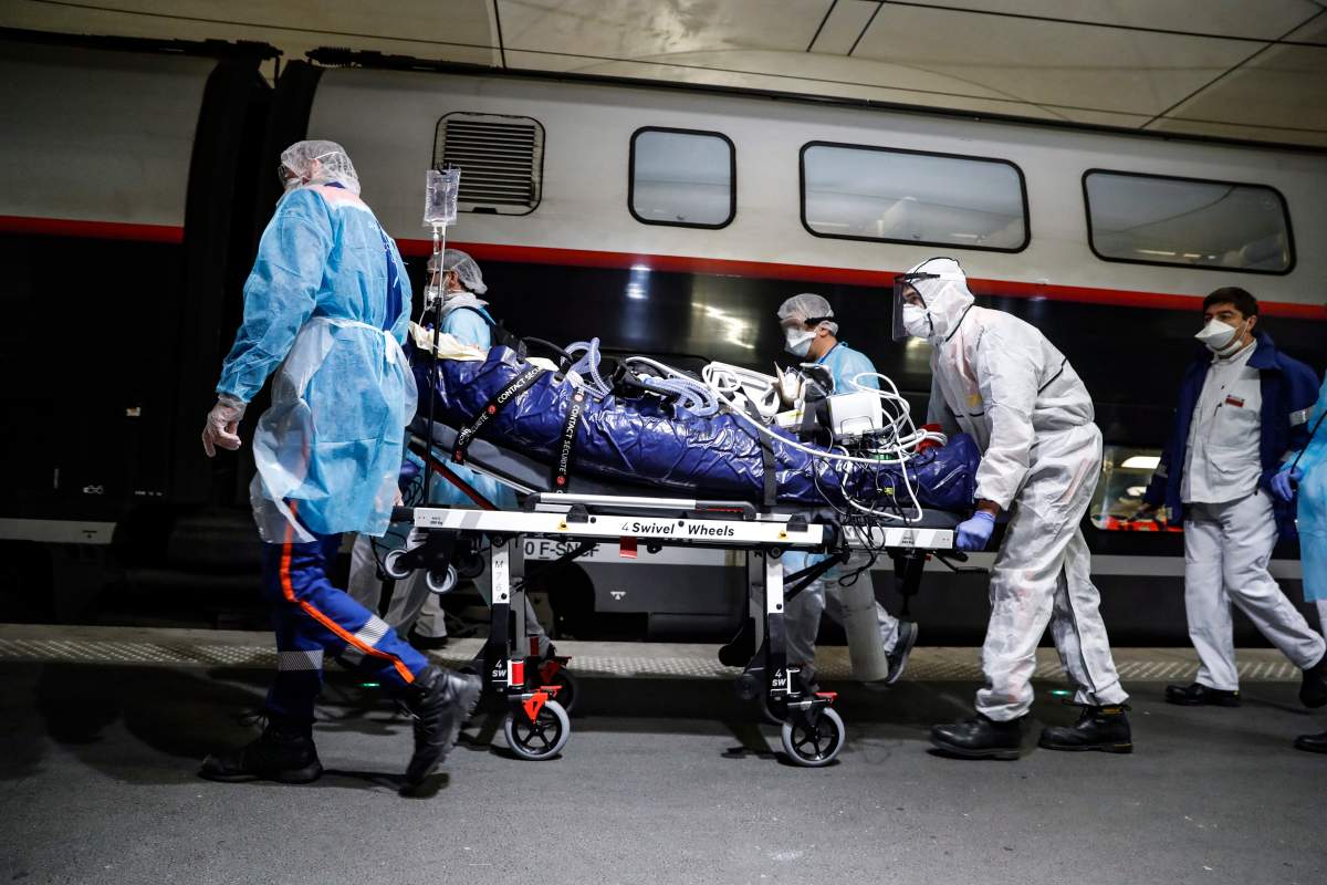 In this April 1, 2020 photo, medical staff transfer a patient infected with the coronavirus to a train at the Gare d’Austerlitz train station in Paris.