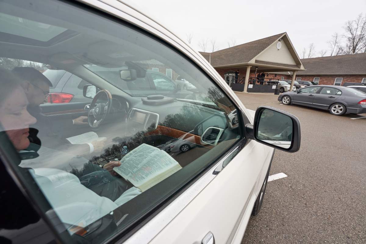 Parishioners read from the bible in their vehicles in the parking lot at The Church of God in Aylmer, Ont., on Sunday, April 26, 2020. Police monitored the service after complaints about the church’s social distancing measures at their drive-in service last week.