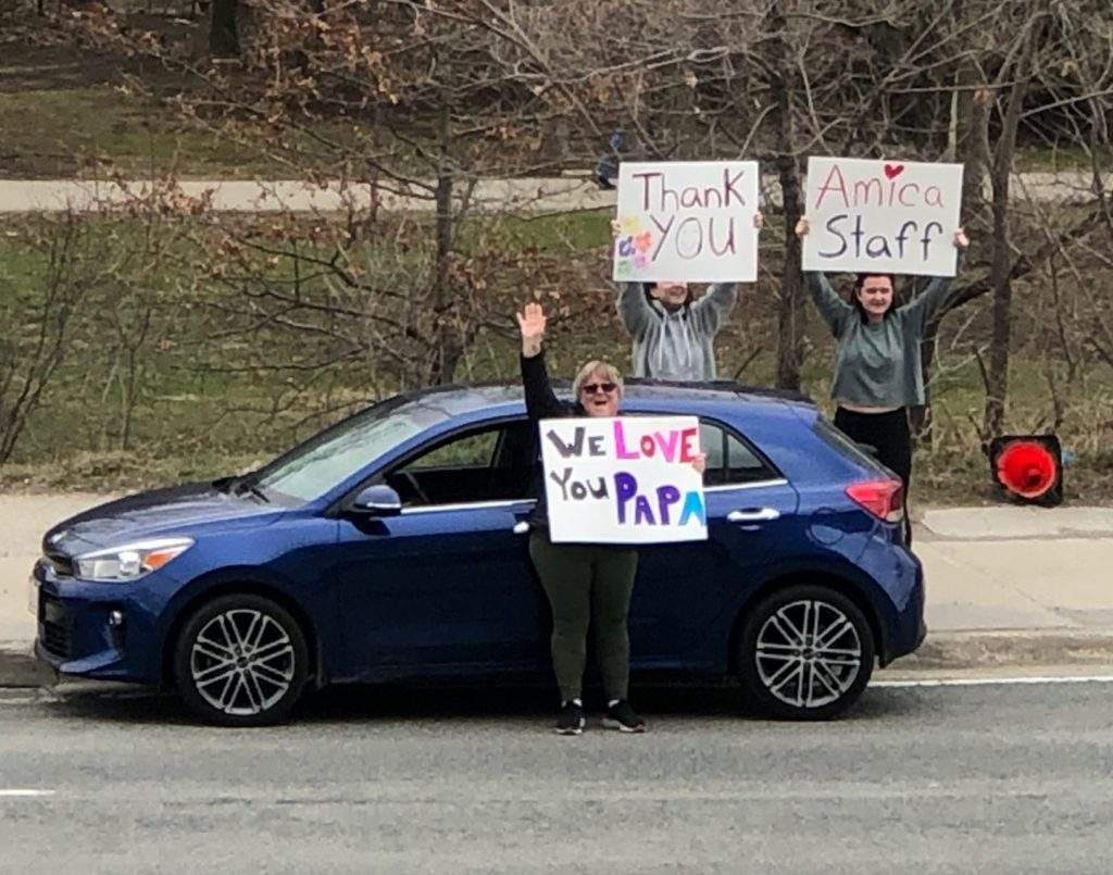 A family waves to a resident from across the street.