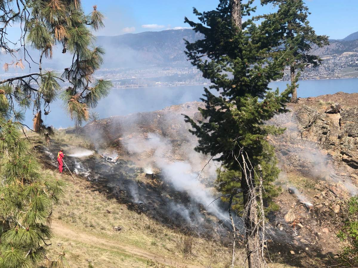 A Kelowna firefighter is seen dousing a grass fire at Bertram Creek Regional Park late Monday morning.