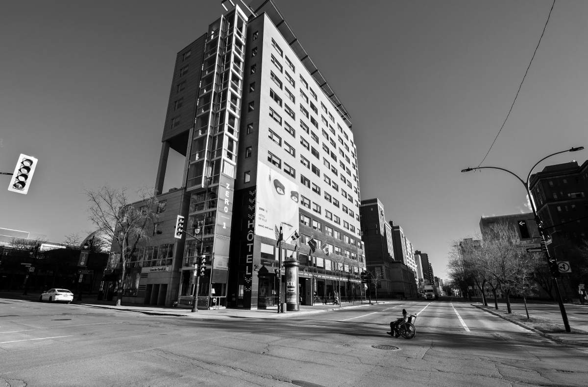A man in a wheelchair crosses a deserted René-Lévesque Boulevard, at St-Laurent Boulevard in downtown Montreal, Sunday March 22, 2020. Phil Carpenter/Global News