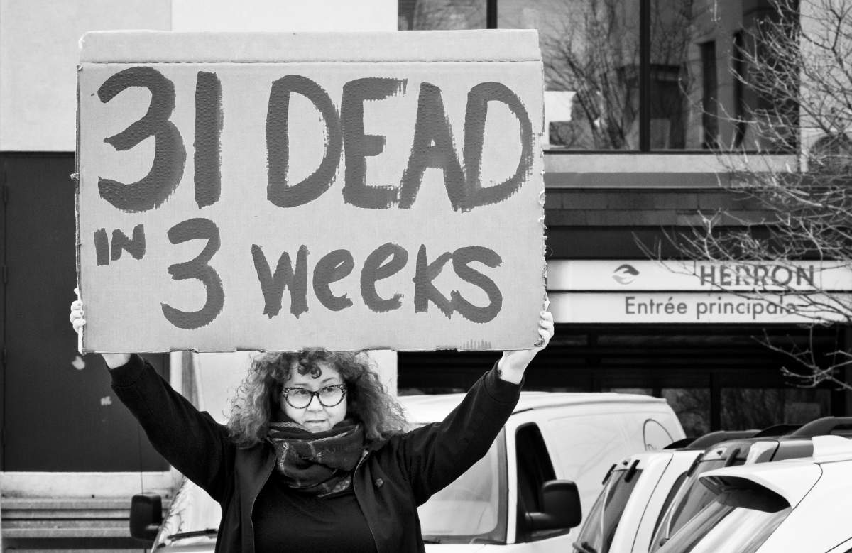 A woman carries a placard protesting the number of deaths at the Maison Herron seniors’ residence in Dorval, Saturday April 11, 2020. Phil Carpenter/Global News