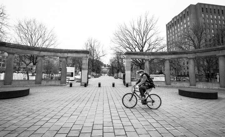 A cyclist wearing a mask rides past the Roddick Gates entrance to an empty McGill University campus on Sherbrooke Street in downtown Montreal, Monday March 23, 2020. Phil Carpenter/Global News
