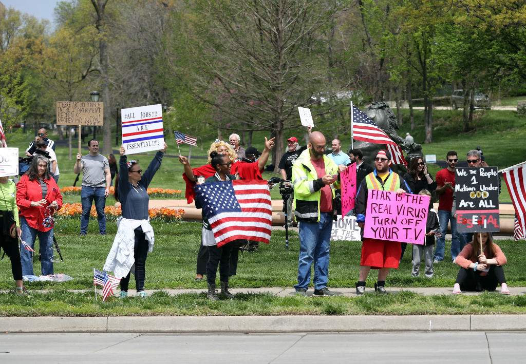 Protesters hold signs encouraging people to demand that businesses be allowed to open up and people allowed to go back to work at the Country Club Plaza on April 20, 2020 in Kansas City, Missouri.