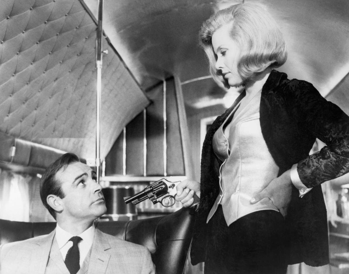 (Original Caption) 1964: In this scene, Honor Blackman as “Pussy Galore” points a gun at Sean Connery as “James Bond.” (Photo by John Springer Collection/CORBIS/Corbis via Getty Images)