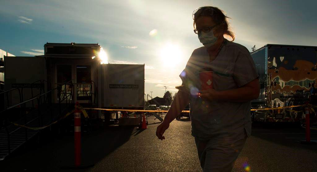 A health-care worker is silhouetted as they walk past the British Columbia mobile medical unit set up outside of Abbotsford Regional Hospital in Abbotsford, B.C. Tuesday, April 14, 2020. The mobile medical unit was deployed to Abbotsford to assist with the COVID-19 outbreak that has occurred at the Mission Correctional Institution.