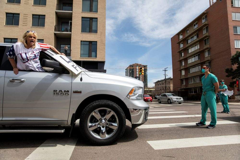 Health-care workers stand in the street in counter-protest to hundreds of people who gathered at the State Capitol to demand the stay-at-home order be lifted in Denver, Colo., on April 19, 2020.