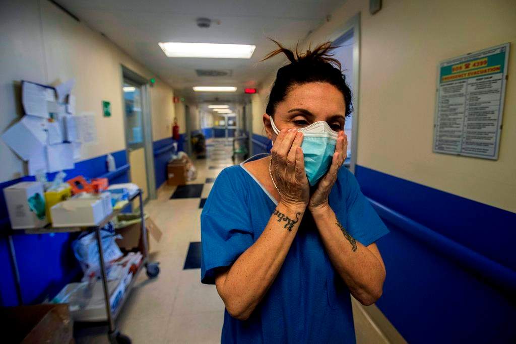 Nurse Cristina Settembrese fixes two masks to her face during her work shift in the COVID-19 ward at the San Paolo hospital in Milan, Italy, April 10, 2020.