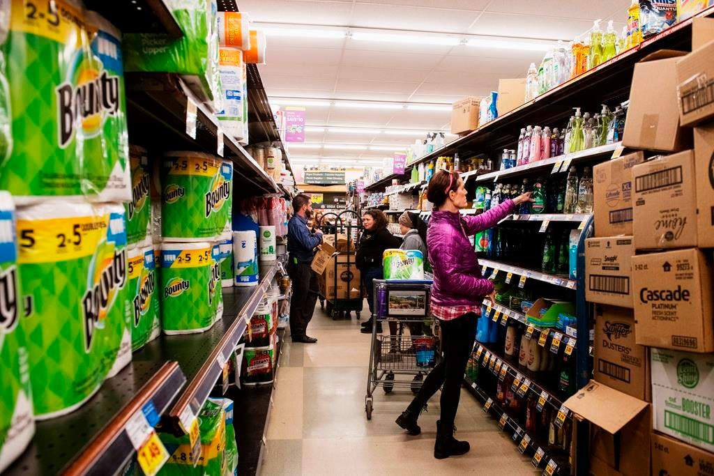 In this March 12, 2020 photo, customers shop for cleaning products as market employees restock shelves in Aspen, Colo.