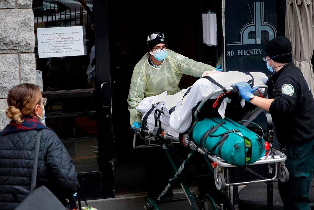 FILE- In this April 17, 2020, file photo, a patient is wheeled into Cobble Hill Health Center by emergency medical workers in the Brooklyn borough of New York.