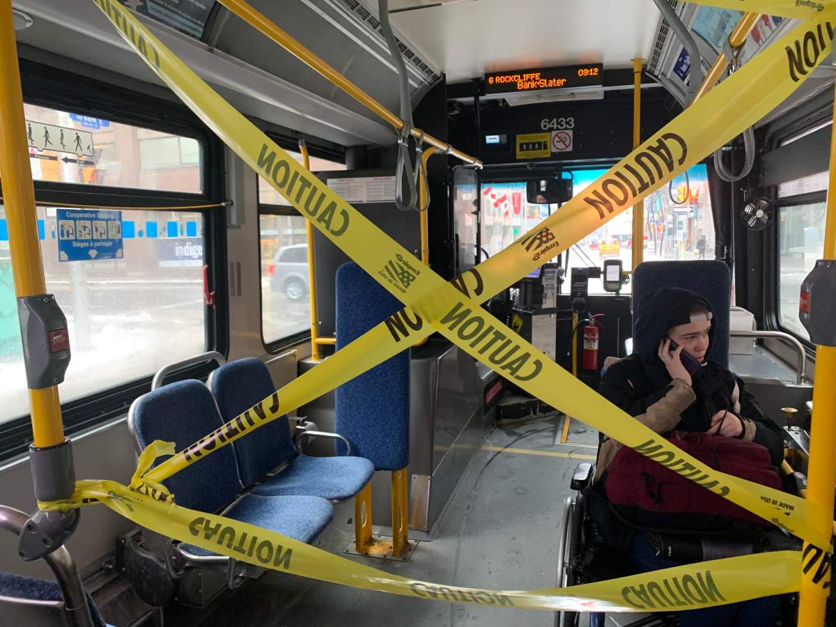 Yellow caution tape separates the driver's cab and the accessible seating area on an OC Transpo bus from the rear area of the vehicle. The transit agency will remove the tape but ask riders to wear masks when service is gradually restored starting in June.