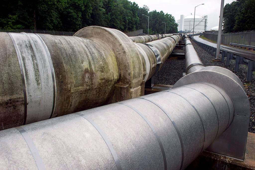 In this June 12, 2014, photo, pipes carrying liquified natural gas to and from a holding tank, seen in background, at Dominion Energy's Cove Point LNG Terminal in Lusby, Md. THE CANADIAN PRESS/AP/Cliff Owen.
