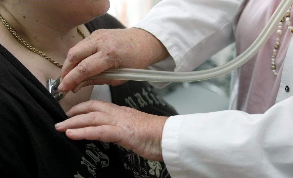 File: A doctor examines a patient with a stethoscope.