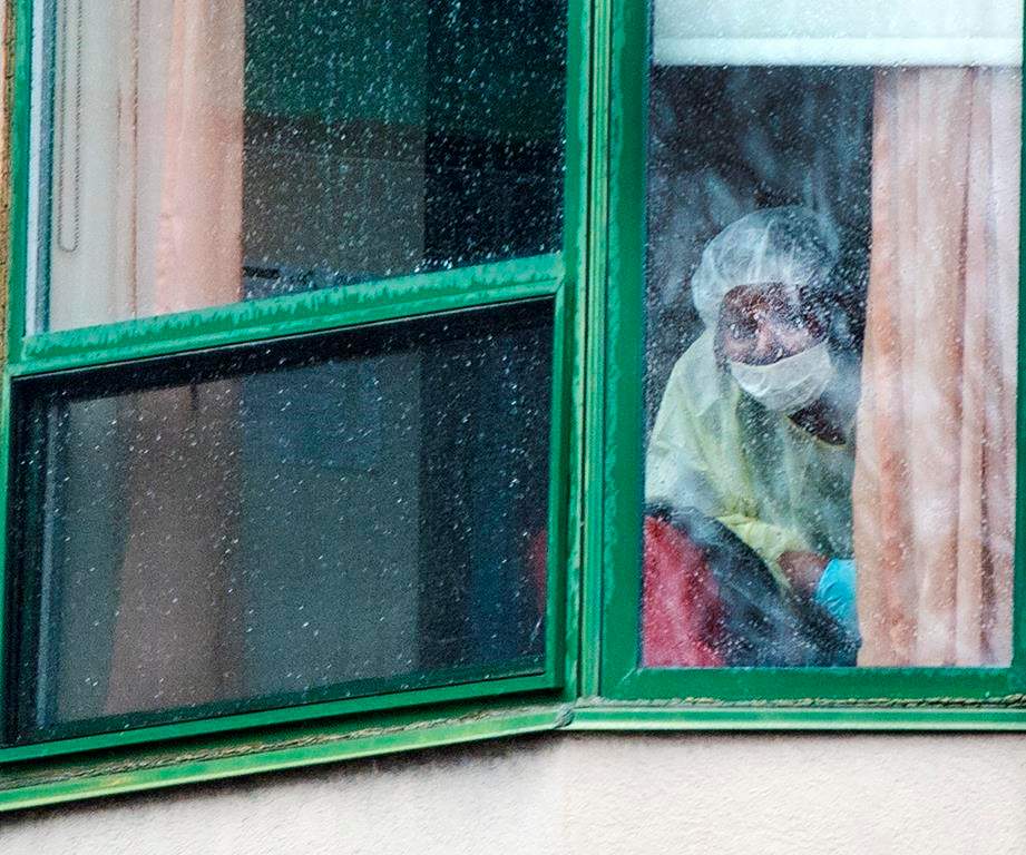 A person wearing protective equipment looks out of a window at the Herron seniors residence Monday April 13, 2020 in Dorval.