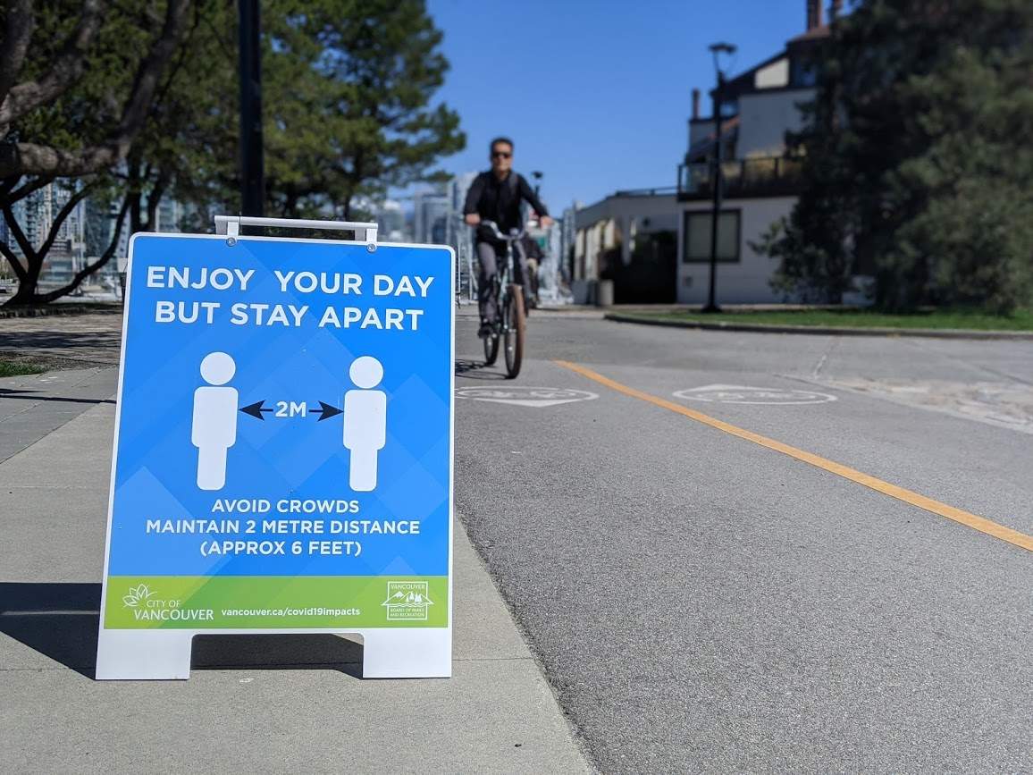 Signs on Vancouver's seawall ask pedestrians and cyclists to stay two metres apart during the COVID-19 pandemic. 