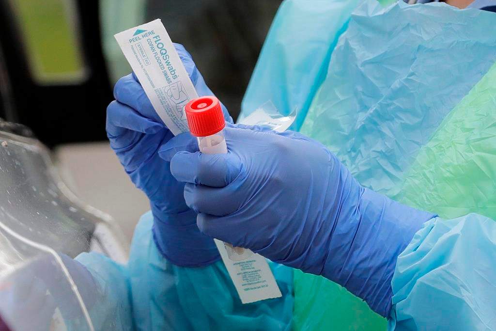 FILEIn this April 2, 2020, file photo a nurse holds a vial and a swab at a drive-up coronavirus testing station at a hospital in Seattle.