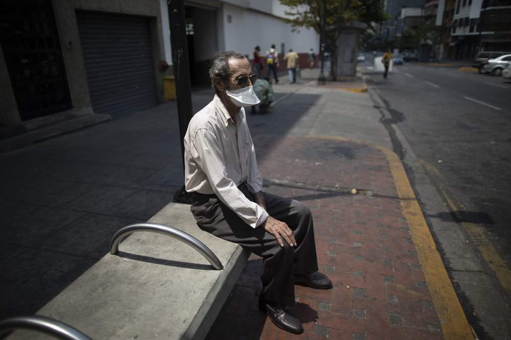 An elderly man wearing a mask to avoid the spread of the new coronavirus suns himself on a bench in Caracas, Venezuela, Sunday, May 24, 2020. 