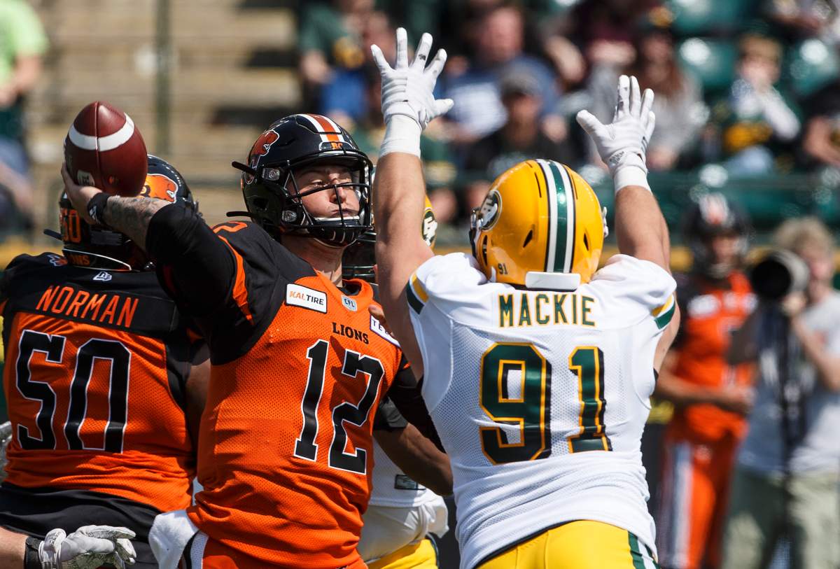 B.C. Lions quarterback Austin Apodaca (12) makes the throw as Edmonton Eskimos Mark Mackie (91) tries to block during first half CFL pre-season action in Edmonton, Alta., on Sunday May 26, 2019.