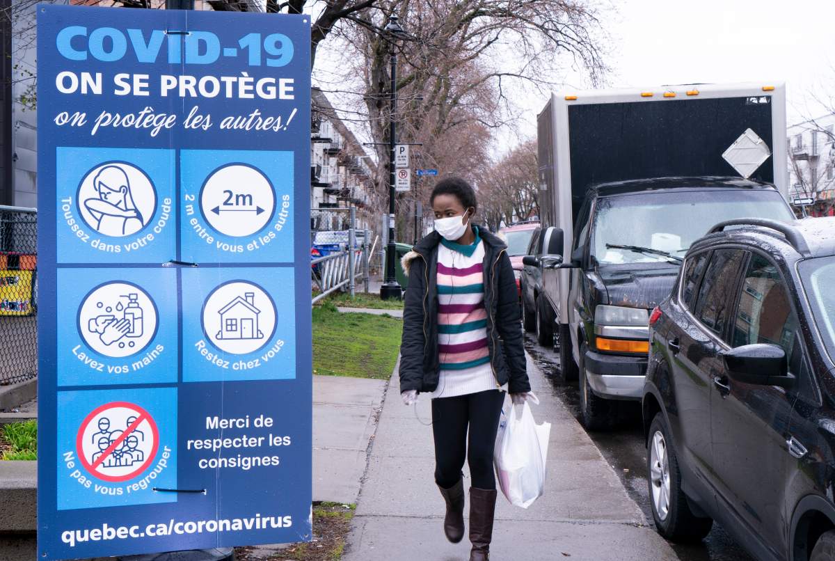 A woman walks past a COVID-19 sign in Montreal North.