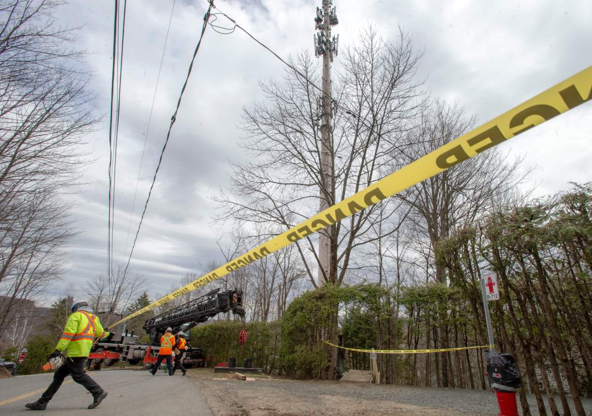 Technicians repair a cell tower after a fire that police are calling suspicious Monday May 4, 2020 in Piedmont, Que. There have been fires at two other cell towers in the area in the past few days.