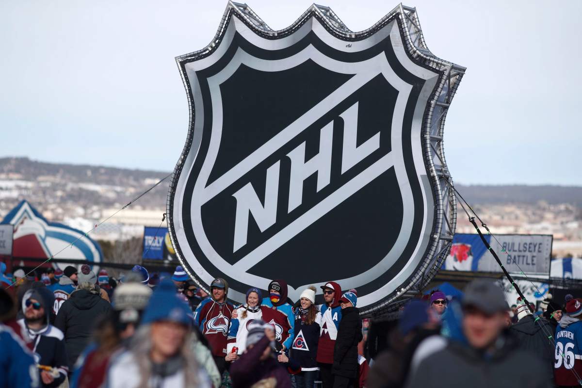  In this Saturday, Feb. 15, 2020, file photo, fans pose below the NHL league logo at a display outside Falcon Stadium before an NHL Stadium Series outdoor hockey game between the Los Angeles Kings and Colorado Avalanche, at Air Force Academy, Colo. 