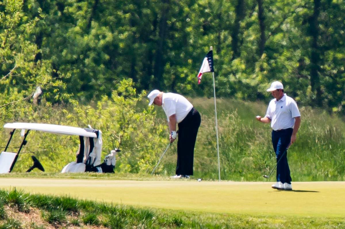 U.S. President Donald J. Trump (C), wearing a white hat and white Polo shirt, plays golf at the Trump National Golf Club in Sterling, Virginia, USA, 23 May 2020.