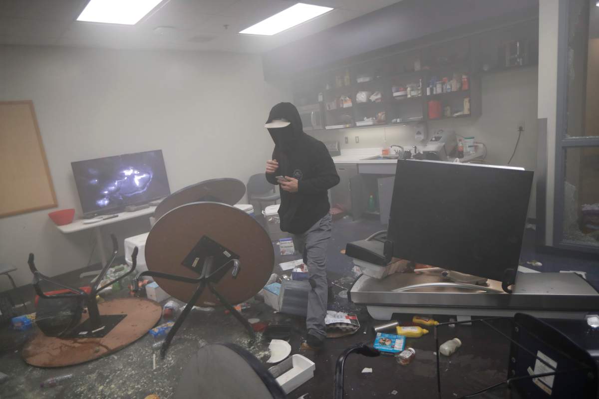 A protester moves around the 3rd Precinct building of the Minneapolis Police Department on Thursday, May 28, 2020, in Minneapolis. (AP Photo/John Minchillo)