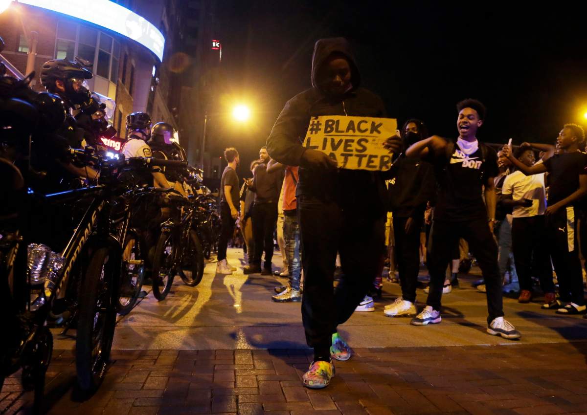 Protesters hold signs and walk past a line of police in downtown Columbus, Ohio, Thursday, May 28, 2020, during a demonstration over the death of George Floyd in police custody Monday in Minneapolis.  (Barbara J. Perenic/The Columbus Dispatch via AP)