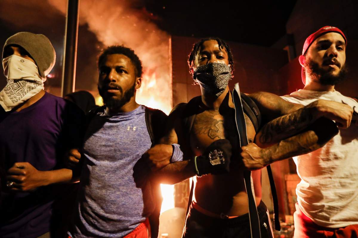 Protestors demonstrate outside of a burning Minneapolis 3rd Police Precinct, Thursday, May 28, 2020, in Minneapolis. (AP Photo/John Minchillo)